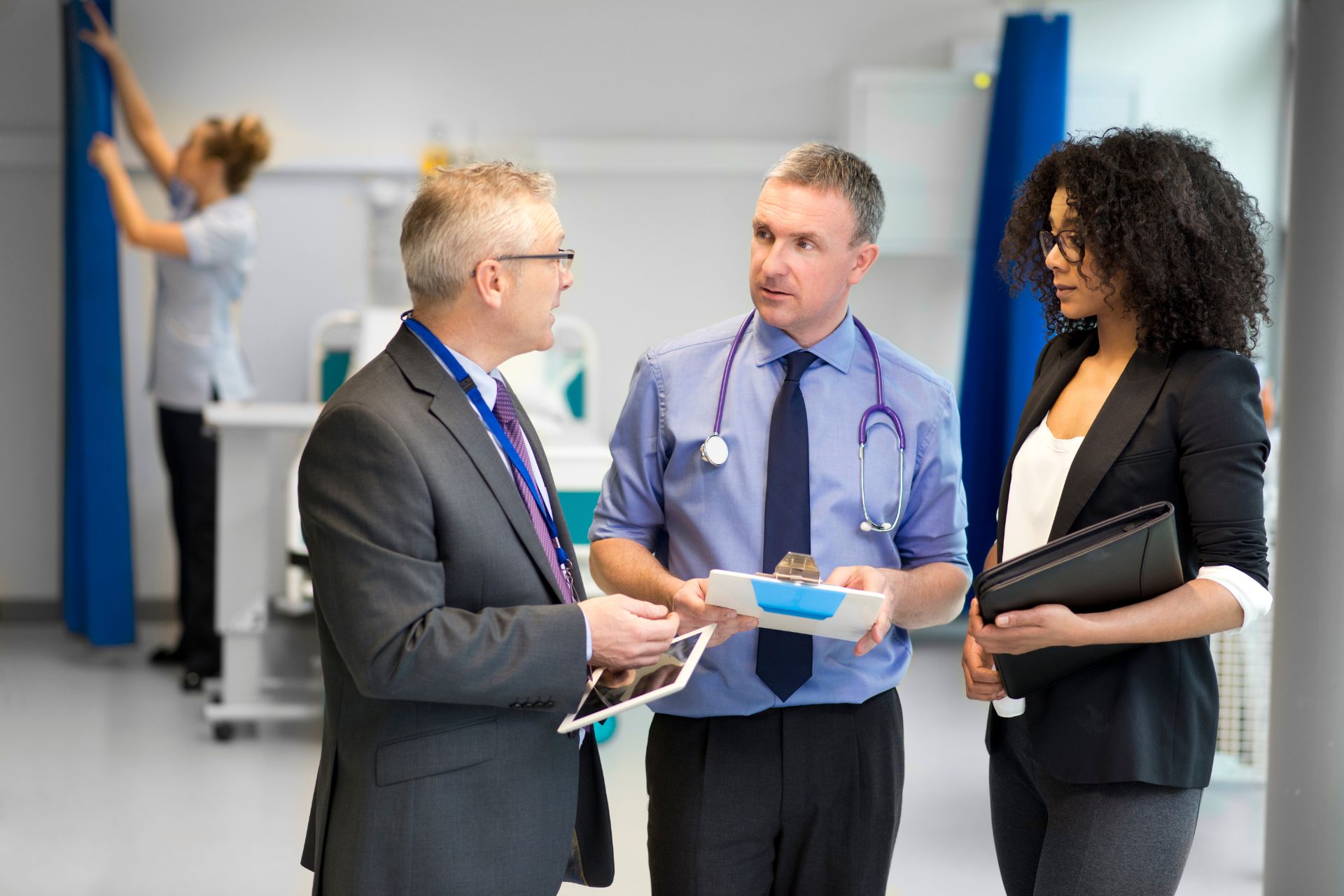 Health care administrator discussing strategies with two hospital staff members, highlighting leadership skills needed as a health care administrator